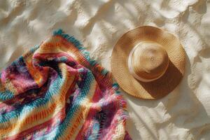 Colorful blanket and straw hat on sandy beach at sunset showcasing vibrant patterns and textures photo