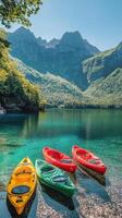 Colorful kayaks resting on a clear lake surrounded by mountains and lush greenery during daylight photo