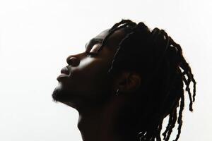 Profile of a man with dreadlocks against a bright background showcasing his thoughtful expression photo