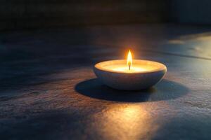 A warm candle glows softly on a reflective surface during golden hour indoors photo