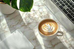 A cozy coffee break with latte art beside a laptop on a marble table in a modern workspace photo