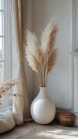 Pampas grass and dried flowers arranged in simple vases on a wooden table against a textured wall photo