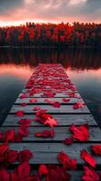 Beautiful sunset over a tranquil lake with a wooden pier covered in red leaves in autumn photo