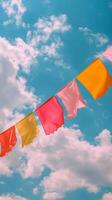 Colorful flags sway under a bright blue sky filled with clouds during a sunny day of celebration photo