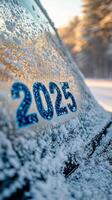 Snow covered vehicle displaying the year 2025 during a winter morning in a rural area photo