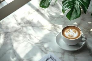 A cozy coffee break with latte art beside a laptop on a marble table in a modern workspace photo