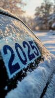 Snow covered vehicle displaying the year 2025 during a winter morning in a rural area photo