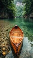 Calm wooden canoe resting on clear water surrounded by lush trees in a tranquil setting photo