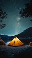 Cozy tent illuminated under a starlit sky in a remote outdoor setting during nighttime photo