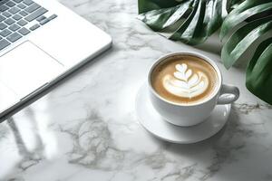 A cozy coffee break with latte art beside a laptop on a marble table in a modern workspace photo