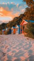Colorful beach huts along a sandy shoreline under a vibrant sunset photo