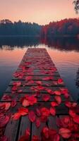 Beautiful sunset over a tranquil lake with a wooden pier covered in red leaves in autumn photo