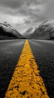 A winding road leads through mountain passes under a dramatic cloudy sky in a remote landscape photo