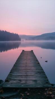Tranquil lake at dawn with a wooden dock and ducks swimming in calm waters photo
