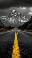 A winding road leads through mountain passes under a dramatic cloudy sky in a remote landscape photo