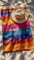 Colorful towel and sunhat on the sandy shore under sunlight on a summer afternoon photo