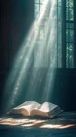 An open book emits glowing particles in a mystical setting with sunlight filtering through photo
