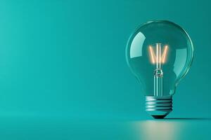 A vintage light bulb illuminated on a green surface beside a plant in soft morning light photo