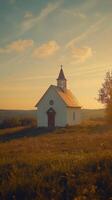 A serene church nestled in a golden meadow under a clear sky in the countryside photo