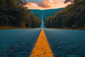 A quiet highway stretches through lush trees under a vibrant sunset in the countryside photo