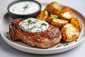 Juicy grilled pork chop served with roasted potatoes and creamy sauce photo