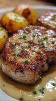 Delicious pork chops served with golden roasted potatoes and creamy sauce in a warm setting photo