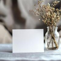 Simple blank card placed next to a vase of dried flowers in a modern interior setting photo