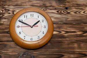 A round clock shows the time against a wooden backdrop photo