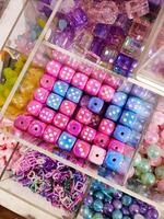 Colorful and vibrant display of bead dice fills a glass case in a store. Accessories things. Do it yourself creativity. photo