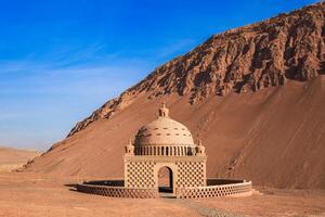 The mud building in uyghur style wirh moutain on background. photo