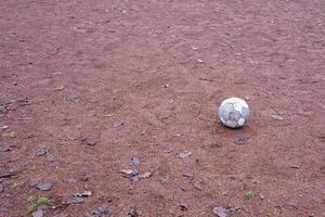 Old deflated soccer ball lying on a deserted gravel playground photo