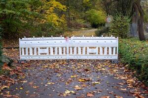 White plastic barrier blocking access to park path during autumn season photo