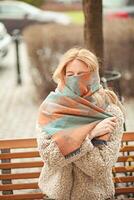 Woman in a cozy scarf walks near classical architecture on a sunny day photo