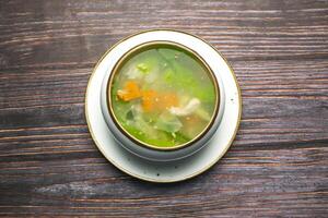Chicken Vegetable soup include cabbage, carrot and belle pepper served in broth isolated on wooden table top view of bangladeshi and thai food photo