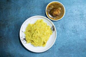 Yellow Moong Dal Khichdi with egg curry served in plate isolated on grey background top view of bangladeshi food photo