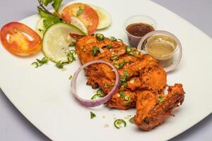 Tandoori Chicken Breast with salad and chutney sauce served in plate isolated on grey background side view of bangladesh, indian and pakistani food photo