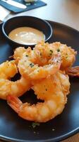 Breaded and fried shrimps with tartar sauce served on a black plate photo