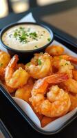Breaded shrimps with tartar sauce garnished with chives, served in a black tray photo