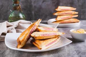 Grilled triangle sandwiches with cheese and sausage on a plate on a table photo