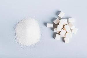 Alternative between lump sugar and granulated sugar on a blue background top view photo