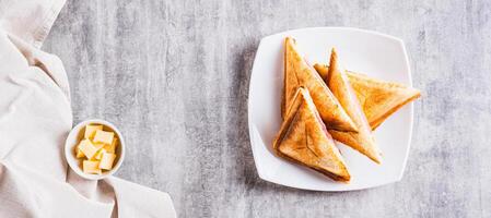 Toasted ham and cheese toasts on a plate on the table top view web banner photo