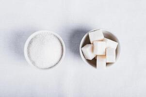 Choosing between granulated sugar and refined sugar in bowls on white background photo