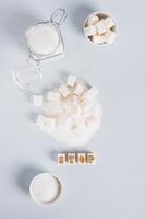 The word stop on pieces of refined sugar as a symbol of refusal from sugar top and vertical view photo