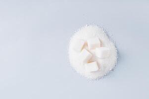 Lump sugar on a pile of granulated sugar on a blue background top view copy space photo