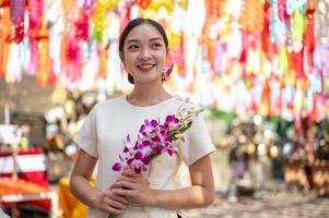A smiling Asian woman stands in a temple with colorful lanterns in the background. photo