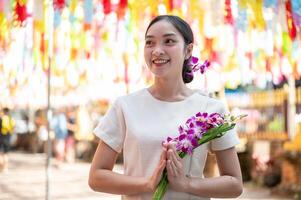 A smiling Asian woman stands in a temple with colorful lanterns in the background. photo