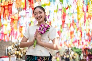 A charming Asian woman stands in a temple with colorful lanterns in the background. photo