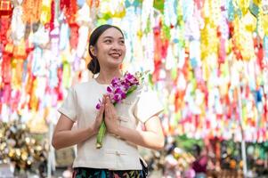 A smiling Asian woman stands in a temple with colorful lanterns in the background. photo