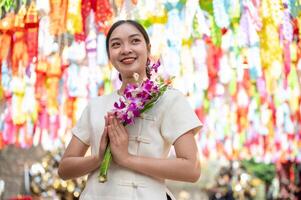 A smiling Asian woman stands in a temple with colorful lanterns in the background. photo