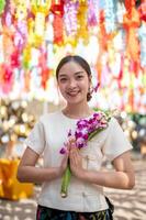 A charming Asian woman stands in a temple with colorful lanterns in the background. photo